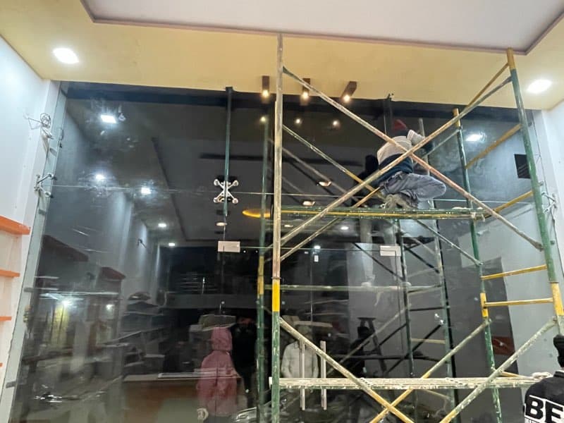 Worker on scaffolding installing a glass storefront