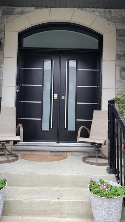 Black double entrance doors with narrow vertical glass inserts and an arched glazed transom.