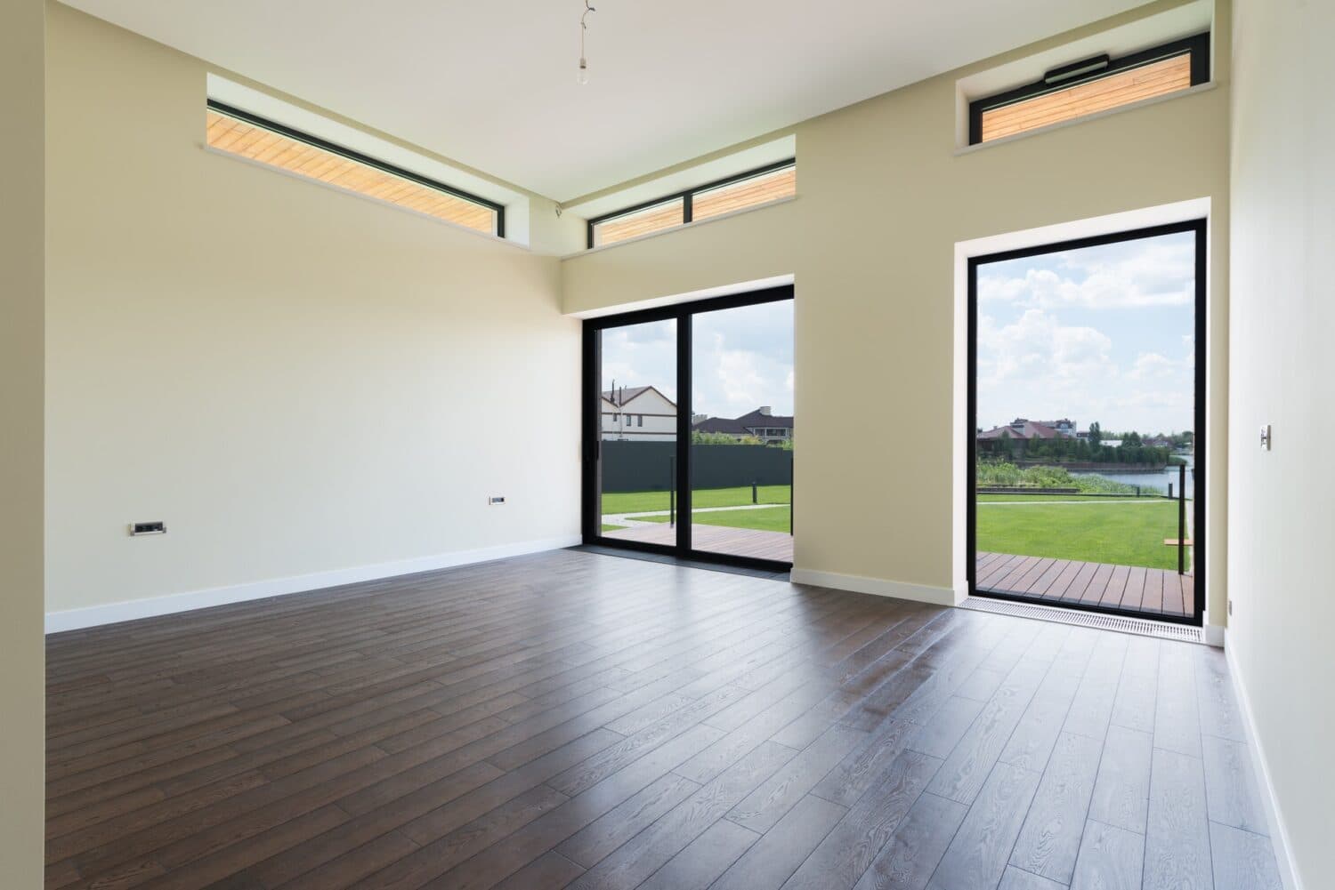 Empty room with black-framed sliding doors and an open glass door to a deck.