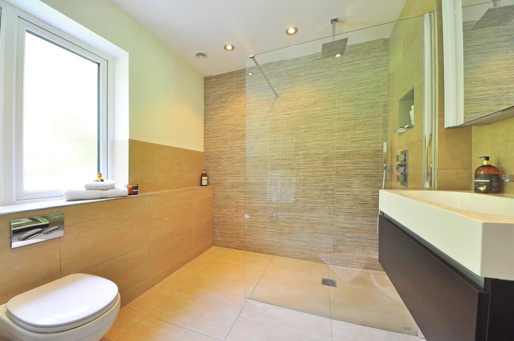 Walk-in shower with a frameless glass panel in a beige bathroom.