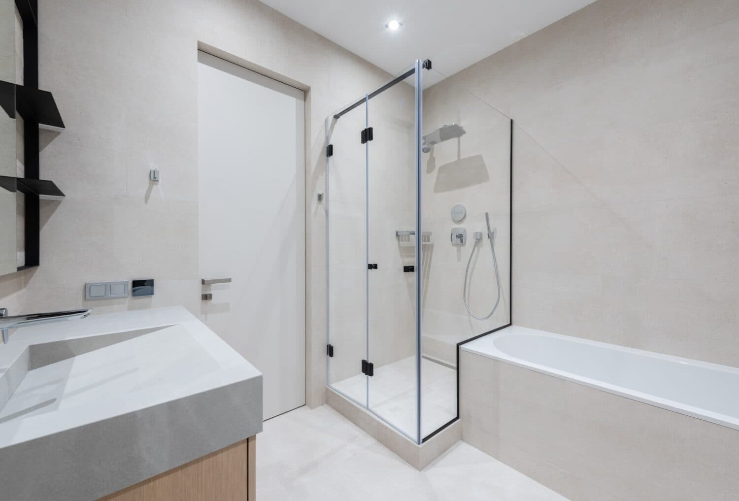 Beige bathroom with a black-framed glass shower beside a bathtub.