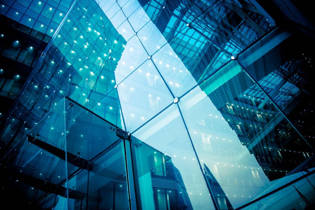 Blue-tinted glass curtain wall seen from below.