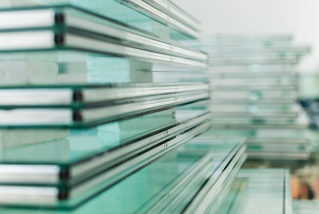 Stacks of clear glass sheets with polished edges.