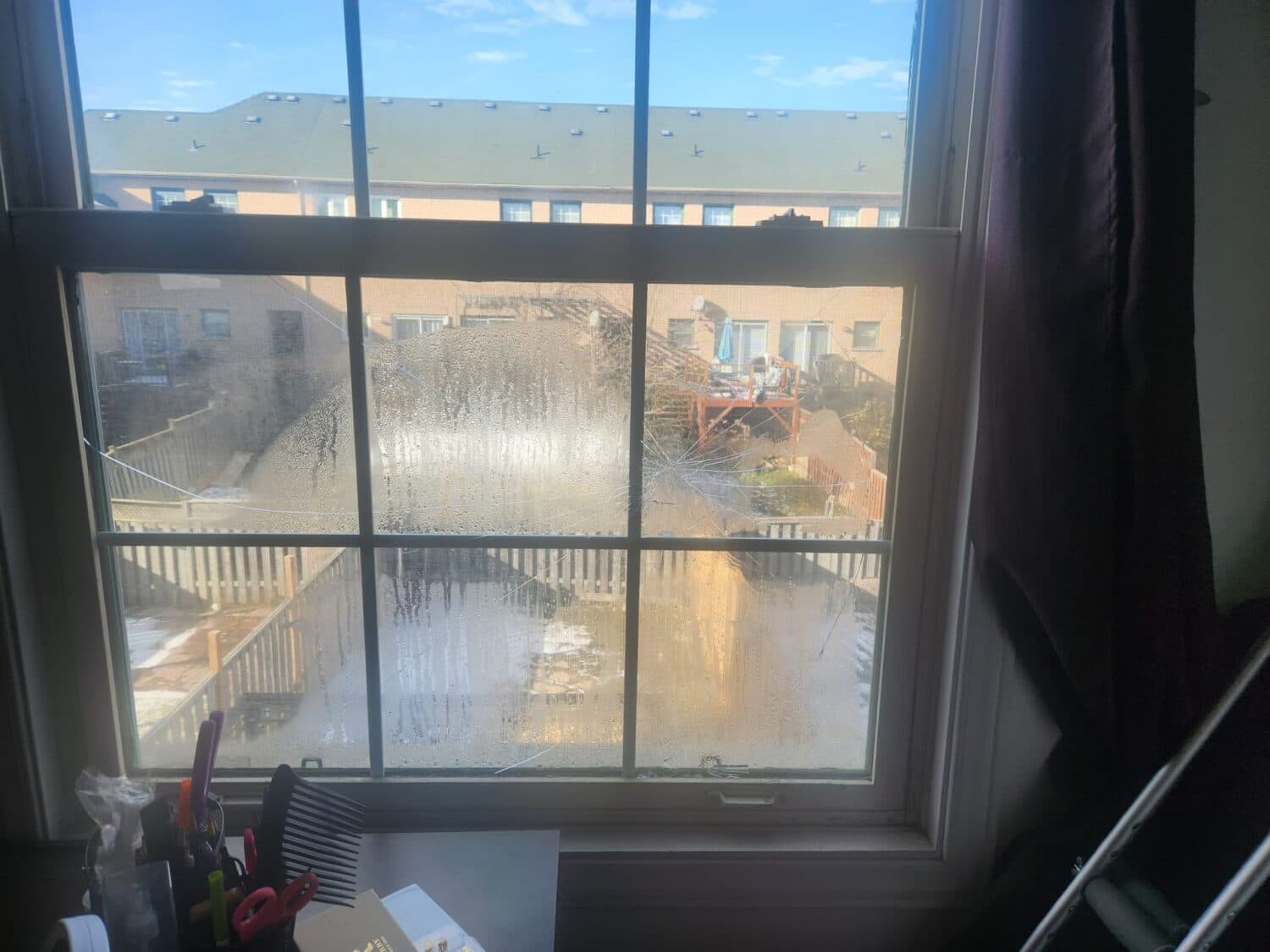 Interior view of a window with cracked lower glass and visible cloudiness.