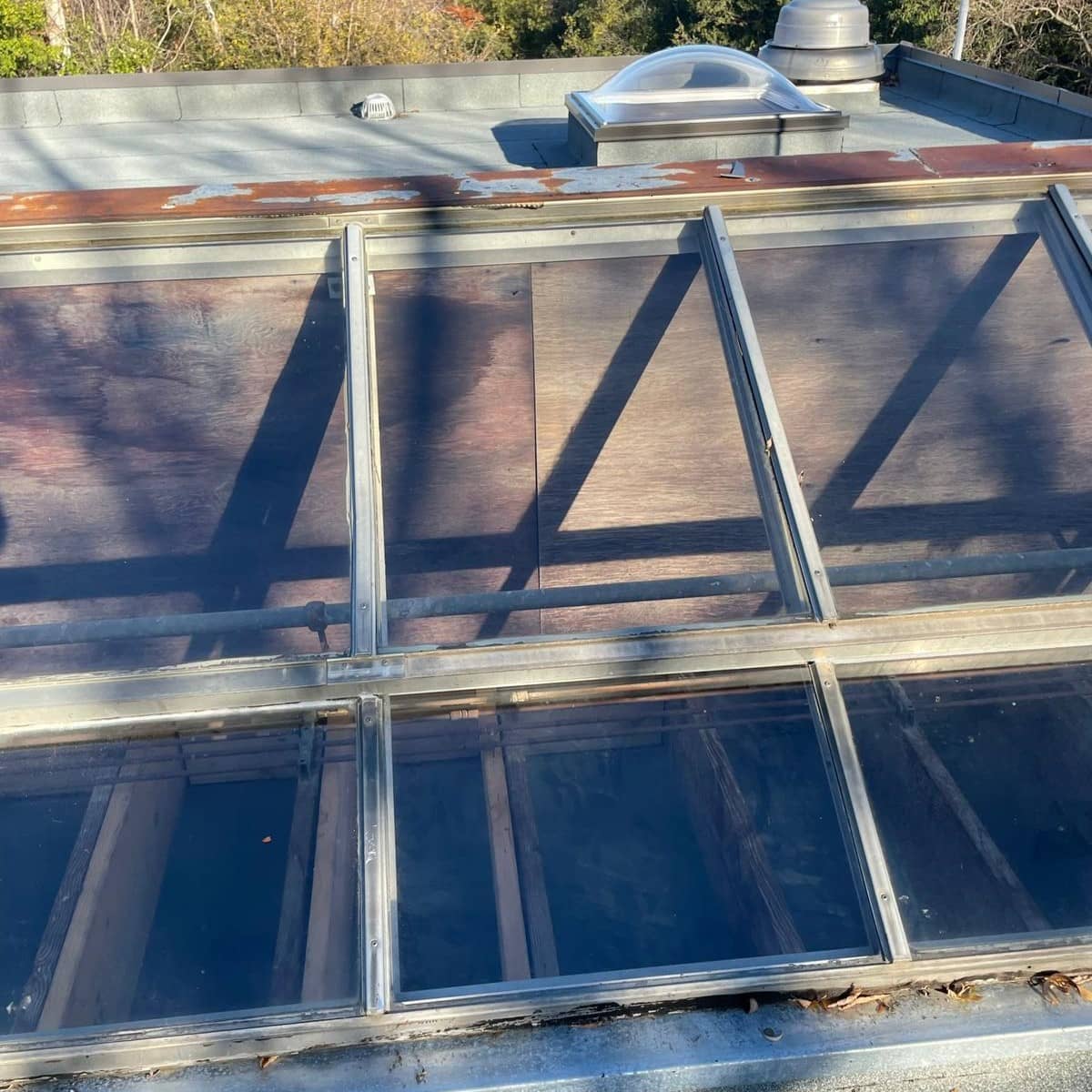Rooftop skylight with several glass panels in a metal frame.