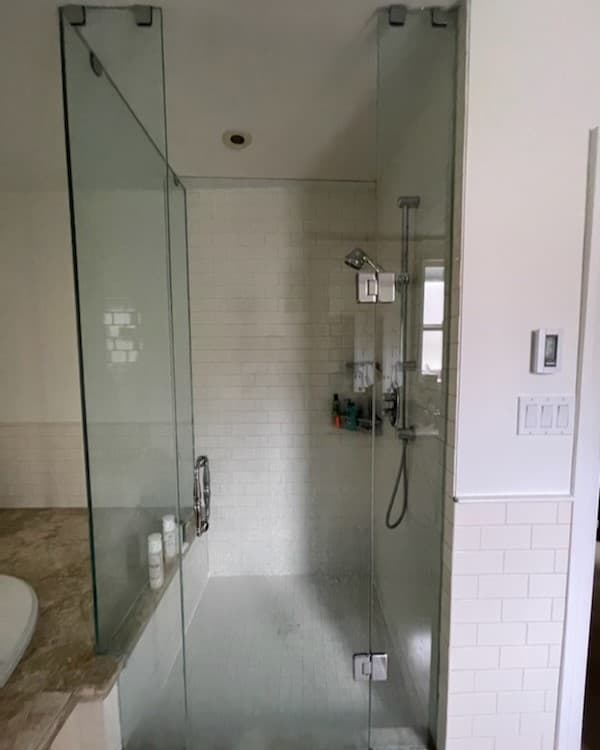 Frameless glass shower enclosure with white subway tile.