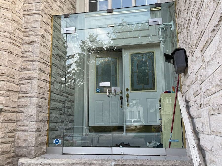 Glass enclosure installed in front of a stone house entrance