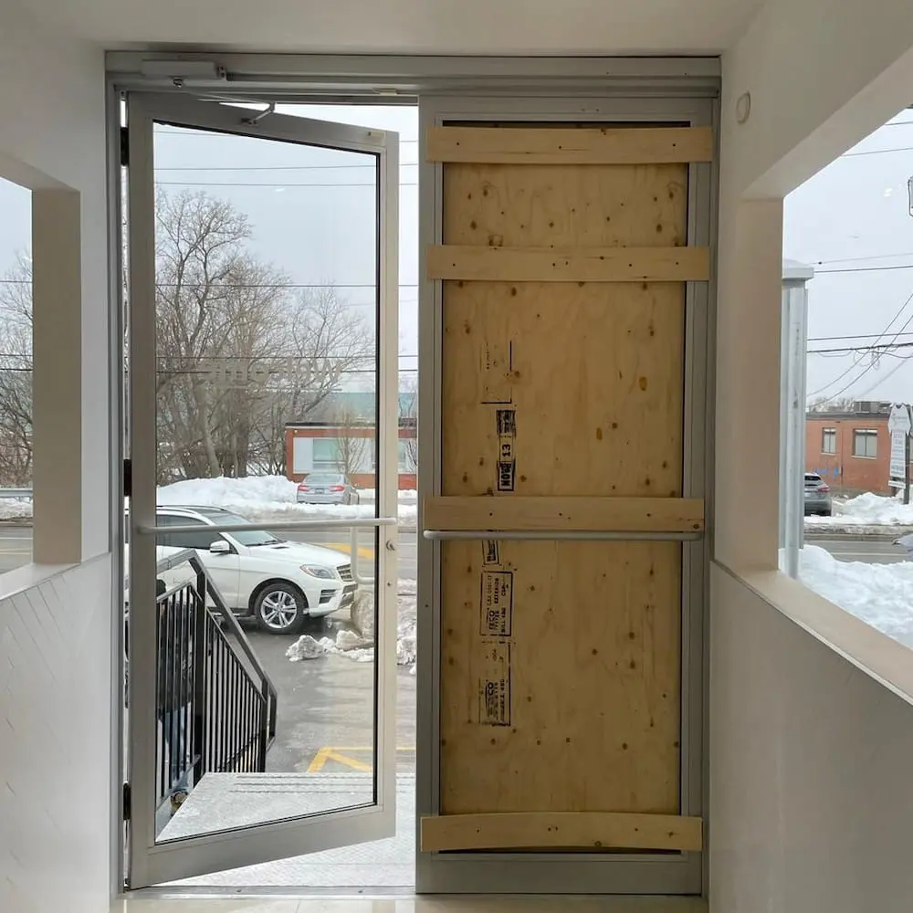 Commercial entrance secured with temporary board-up after glass damage
