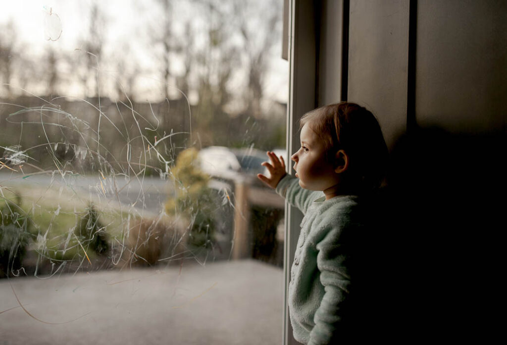 kid starring through transparent glass window