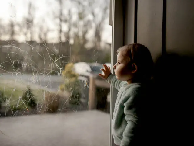 Toddler Looking Out Through Scribbled On Glass Door